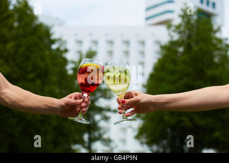 Hand holding cocktail verres trinquer ensemble à l'extérieur. Banque D'Images