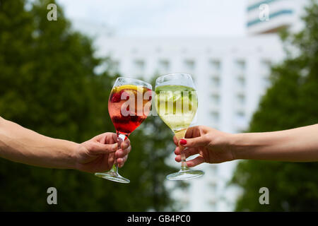 Hand holding cocktail verres trinquer ensemble à l'extérieur. Banque D'Images