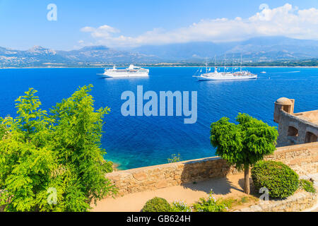 Vue sur les bateaux de croisière sur la mer bleue d'amarrage dans la baie de Calvi, Corse, France Banque D'Images