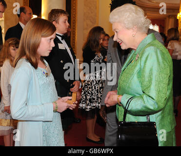 La reine Elizabeth II de Grande-Bretagne présente un insigne d'or Blue Peter à Elena Byrne, 11 ans, d'Irlande du Nord, qui a recueilli des fonds et écrit de la poésie pour les personnes souffrant de fibrose kystique, lors d'une réception marquant le 50e anniversaire du programme de télévision pour enfants de la BBC Blue Peter à Buckingham Palace, Londres. Banque D'Images