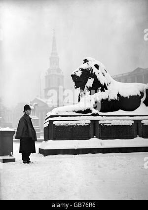 Un policier regarde l'un des lions de la colonne de Nelson recouverts d'une couche de neige, après une forte chute de neige à Londres. Banque D'Images