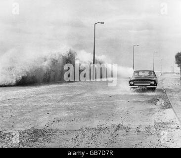 Le temps violent et les mers fortes batlent le chemin Sandgate, à Hythe, près de Folkestone, dans le Kent, couvrant la promenade avec des cailloux et de minuscules pierres, ce qui rend les conditions de conduite précaires. Banque D'Images