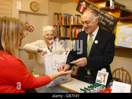 L'ancien chef du Parti conservateur Michael Howard aide le membre du personnel Pauline Bryant (au centre) à servir un client jusqu'au magasin Barnardo de Folkestone, dans le Kent, dans le cadre de la journée Barnardos Make a Difference. Banque D'Images