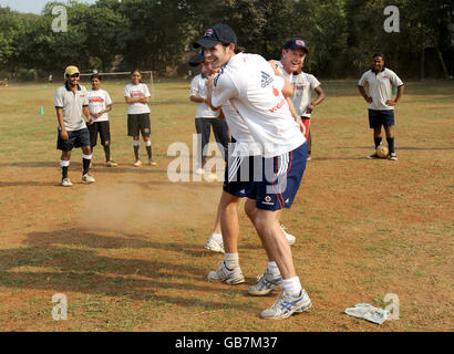 Les joueurs de cricket de l'Angleterre James Anderson (avant) Luke Wright et Paul Collingwood (droite) jouent un jeu de football avec des enfants de l'organisation Magic bus qui encourage les enfants des quartiers de taudis et de pavés de Mumbai à développer des compétences de vie au sol de BPT à Mumbai, en Inde. Banque D'Images