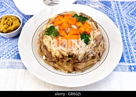 Boeuf et porc en gelée avec les carottes et le persil sur une assiette, sur fond de nappes en lin moutarde Banque D'Images