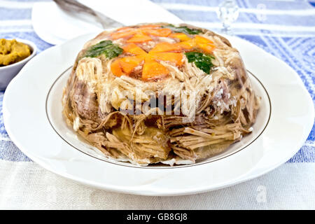 Boeuf et porc en gelée avec les carottes et le persil sur la plaque sur un fond de moutarde lin bleu Banque D'Images