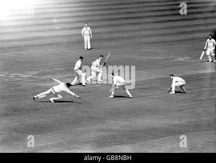 Desmond Eagar (l) du Hampshire plonge pour faire un tir Colin Ingleby-MacKenzie (c) du MCC, observé par le gardien de cricket Leo Harrison (seconde l) Banque D'Images