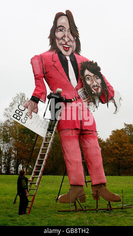 L'artiste Frank Shepherd (en haut) ajoute la touche finale à l'effigie de Jonathan Ross et Russell Brand, qui tient l'échelle, avant la célébration de Bonfire Night à Edenbridge, dans le Kent. Banque D'Images
