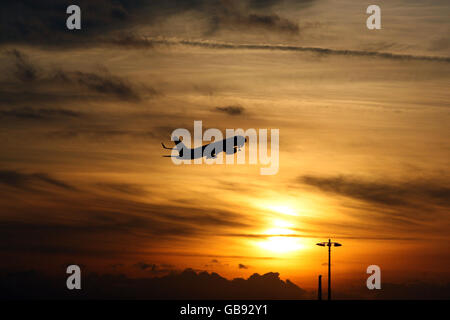 Un avion part de l'aéroport de Heathrow, Middlesex, au coucher du soleil d'hiver. Banque D'Images