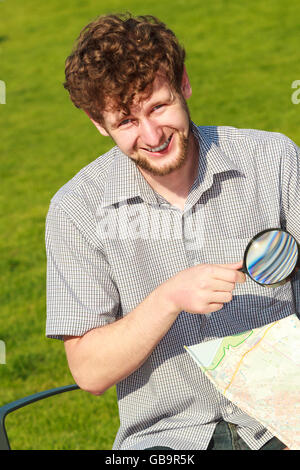 Concept voyages d'été. Les jeunes gens en vacances touristiques en ville à la recherche d'instructions sur la carte holding magnifying glass Banque D'Images