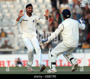 Harbhajan Singh, en Inde, célèbre avec MS Dhoni après avoir pris le cricket de Kevin Pietersen, lbw pour 144 au cours de la troisième journée du deuxième test au Punjab Cricket Association Stadium, Mohali, en Inde. Banque D'Images