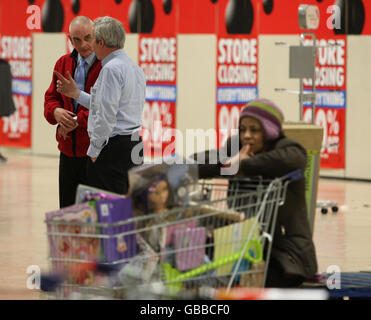 Un acheteur avec un chariot emballé prend une pause au cours de la dernière journée de négociation au magasin Woolworths d'Édimbourg alors que les membres du personnel parlent en arrière-plan. Banque D'Images