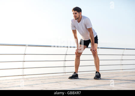 Toute la longueur du beau jeune fatigué sportsman standing on pier Banque D'Images