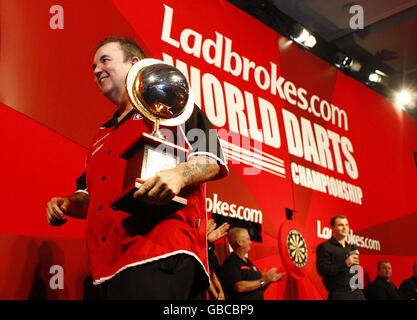 Le champion Phil Taylor sort de la scène avec le trophée des gagnants sous son bras après sa victoire à la finale du Championnat du monde Ladbrokes.com à Alexandra Palace, Londres. Banque D'Images