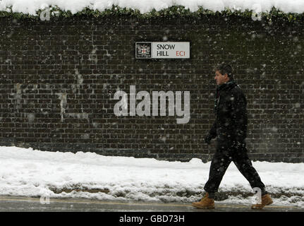 Un homme marche à travers la neige qui tombe sur Snow Hill, dans la ville de Londres. Banque D'Images