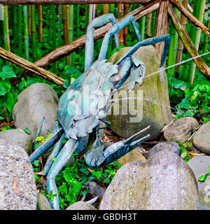 Sculpture en métal oxydé partiellement crabes eau sprays aux passants une forêt de bambous cannes Banque D'Images