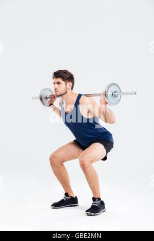 Beau jeune homme sportif faisant squats barbell avec over white background Banque D'Images