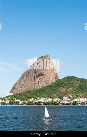 Seul voilier passe l'affichage classique de Pao de Acucar Sugarloaf Mountain permanent au-dessus de la baie de Botafogo, à Rio de Janeiro, Brésil Banque D'Images