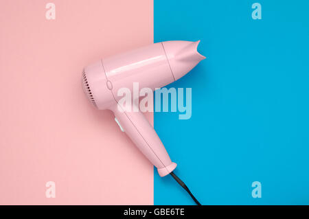 Sèche-cheveux rose sur fond de papier bleu et rose Banque D'Images