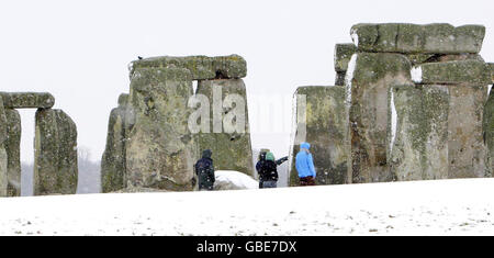 Les visiteurs se enveloppent dans le froid en marchant sur le site du patrimoine mondial de Stonehenge près de Salisbury, Wiltshire, dans la neige aujourd'hui. Banque D'Images