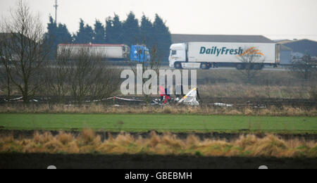 Des experts de la Direction des enquêtes sur les accidents aériens (AAIB) arpenchent l'épave d'un hélicoptère dans un champ proche de l'autoroute M180 à Sandtoft, près de Doncaster. Banque D'Images