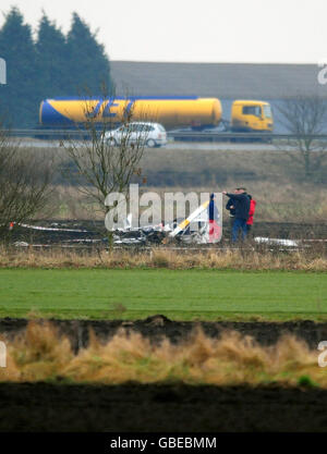 Des experts de la Direction des enquêtes sur les accidents aériens (AAIB) arpenchent l'épave d'un hélicoptère dans un champ proche de l'autoroute M180 à Sandtoft, près de Doncaster. Banque D'Images