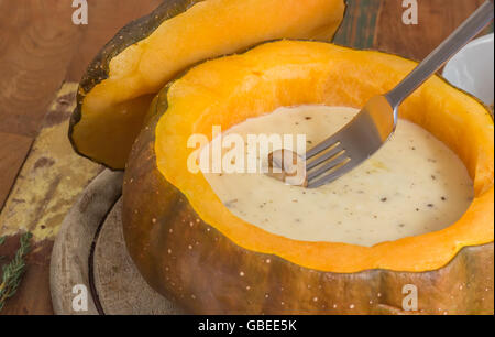 Fondue dans une citrouille rôties avec un champignon châtaigne sur une fourchette Banque D'Images