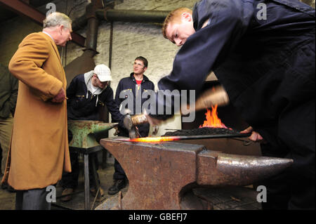 Le Prince de Galles (à gauche) discute avec des étudiants qui étudient le blacksmitthing, lors d'une visite au Centre de compétences rurales de Cirencester, Gloucestershire. Banque D'Images