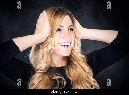 Cheerful surpris Femme blonde sur fond sombre. Banque D'Images