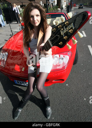 Keris Chandler jouant une guitare Brian Eastwood par une Ferrari Superamerica appartenant à Rod Stewart devant le Hard Rock café de Londres. Banque D'Images