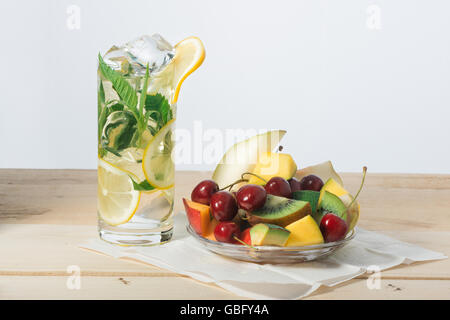 Tranches de fruits, de cerise et de citron verre avec de la glace dans un verre sur la surface de panneaux en bois Banque D'Images