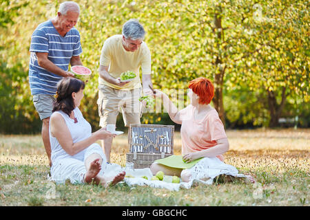 Heureux les aînés de faire un pique-nique au parc manger des fruits en été Banque D'Images