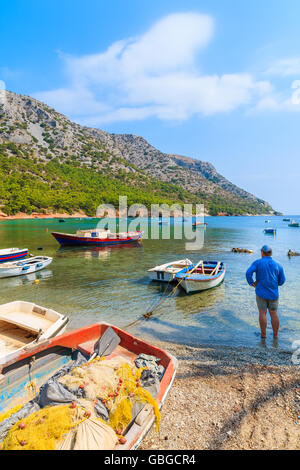 Parmi les bateaux de pêche pêcheur debout sur une plage isolée, l'île de Samos, Grèce Banque D'Images