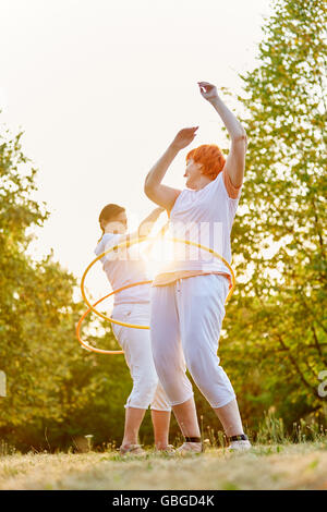 Deux hauts femme faisant des exercices de remise en forme avec des cerceaux dans le parc en été Banque D'Images