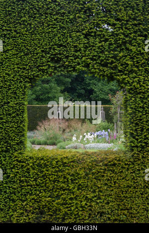 Regarder à travers un trou dans la haie d'if dans un jardin à Waterperry jardins, Wheatley, l'Oxfordshire. L'Angleterre Banque D'Images