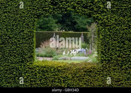 Regarder à travers un trou dans la haie en un jardin à Waterperry gardens, Wheatley, l'Oxfordshire. L'Angleterre Banque D'Images