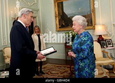 La reine Elizabeth II de Grande-Bretagne présente au sénateur américain John Warner un Chevalier honoraire commandant pour son travail de renforcement de l'alliance militaire américano-britannique. Il est surveillé par sa fille Mary Conover (présentée) et d'autres membres de sa famille au palais de Buckingham. Banque D'Images