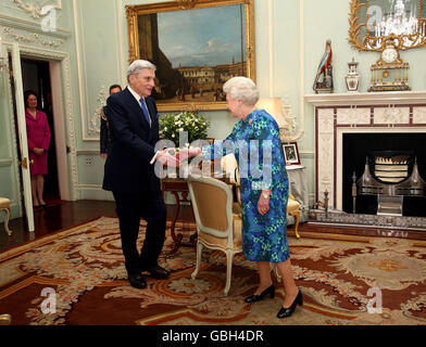 La reine Elizabeth II de Grande-Bretagne présente au sénateur américain John Warner un Chevalier honoraire commandant pour son travail de renforcement de l'alliance militaire américano-britannique. Il est surveillé par sa femme Jeanne Warner (à gauche) au Palais de Buckingham. Banque D'Images