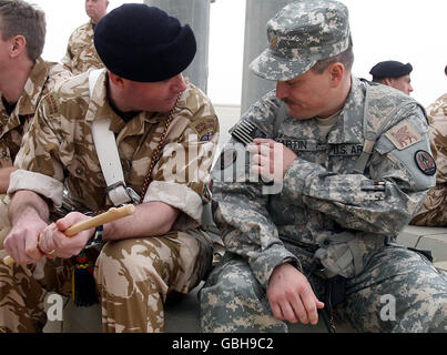 Couleur le Sgt Paul Annet de la bande royale des Marines (à gauche) parle du drapeau américain sur l'uniforme du major américain Philip Martin lors de la cérémonie de remise du commandement militaire des forces de la coalition à Bassora, en Irak, lors d'une cérémonie à l'aéroport international de Bassora. Banque D'Images