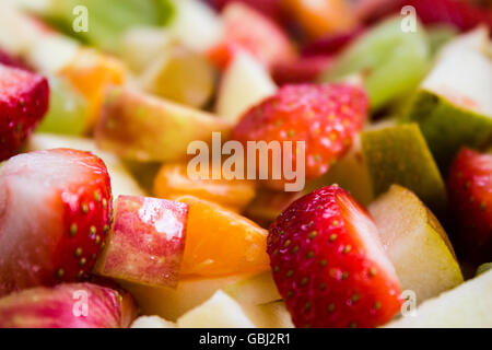 Un mélange coloré de salades de fruits, y compris les fraises, raisins, pommes vertes, poires, et des oranges. Banque D'Images