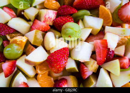 Un mélange coloré de salades de fruits, y compris les fraises, raisins, pommes vertes, poires, et des oranges. Banque D'Images