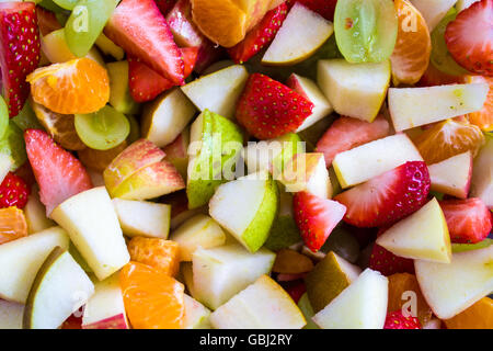Un mélange coloré de salades de fruits, y compris les fraises, raisins, pommes vertes, poires, et des oranges. Banque D'Images
