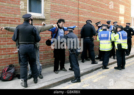 Les policiers arrêtent et interrogez certaines personnes à la suite d'un raid sur une adresse à Rampart Street, dans l'est de Londres, en relation avec le désordre survenu hier dans la ville de Londres. Banque D'Images