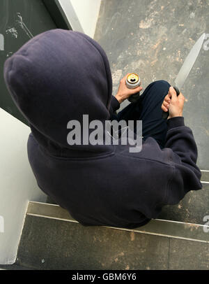 Stock de crime.IMAGE POSÉE PAR LE MODÈLE.Une vue générale d'un homme dans un sweat à capuche tenant un couteau et buvant une cantine. Banque D'Images