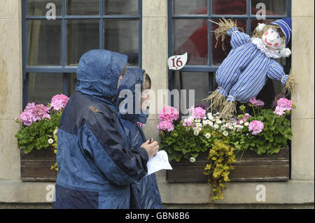 Les gens brave la pluie pour prendre part à un sentier de fraiches dans le village de Norton St Philip, Somerset, et de cocher le scarecrow numéro 16 Andy Pandy, car tous les personnages de fraiches sont basés sur des personnages de programme de télévision pour enfants. Banque D'Images