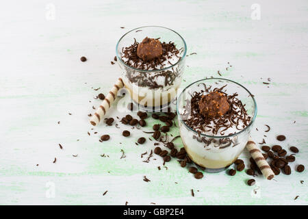 Chocolat café crémeux dans des verres à cocktails sur fond vert clair. Dessert avec café cacao. Banque D'Images