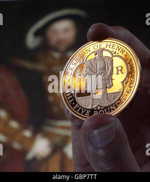 Une nouvelle pièce de la couronne produite par la monnaie royale pour commémorer le 500e anniversaire de l'accession de Henri VIII au trône, devant le portrait de Henry VIII dans le Grand Hall de l'hôpital St Bartholomew à Smithfield, Londres. Banque D'Images