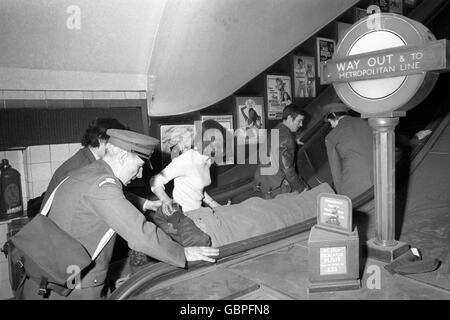 Une des personnes blessées dans l'écrasement du tube à la station de métro Moorgate est transportée sur un escalier roulant en route vers une ambulance d'attente. Banque D'Images