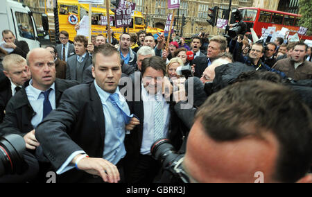 Les gardes du corps précipitent le chef du BNP Nick Griffin (au centre, cravate rayée) dans sa voiture alors qu'il abandonne une conférence de presse devant le Parlement de Londres après que les manifestants l'ont saccagé et jeté des œufs. Banque D'Images