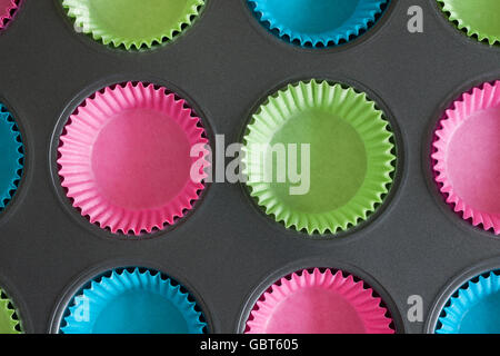 Cake ou muffin tin avec du papier coloré cas utile pour les concepts de cuisson Banque D'Images